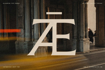 The Arcilla "Æ" ligature at monumental scale in cream, set against a blurred classical colonnade — editorial display use.