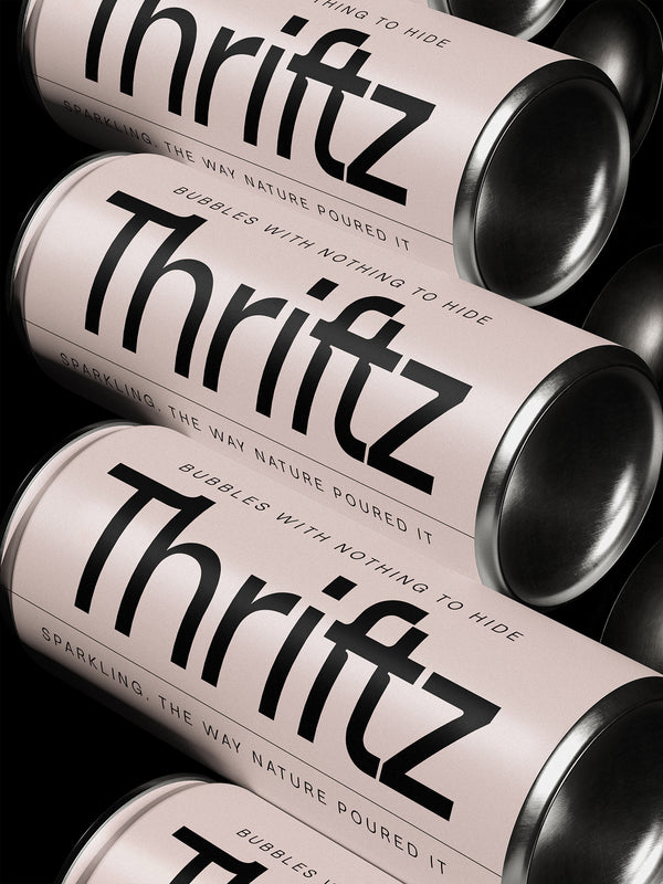 SLTF Ryecroft packaging mockup. Three blush pink drinks cans with brushed metal ends lie diagonally across a black ground. The brand name Thritz is set very large in a heavy weight down the length of each can, with the f and t drawn tight together. Curved letterspaced capitals wrap the rims reading sparkling, the way nature poured it, and bubbles with nothing to hide.