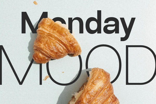 SLTF Ryecroft specimen on a pale mint ground. Monday is set in a heavy black weight across the top and MOOD in a thin outline weight below it, both at large size. Two croissants sit on the surface, one overlapping the M of Monday and one breaking into the O of MOOD, with crumbs scattered across the background and soft shadows falling to the right.