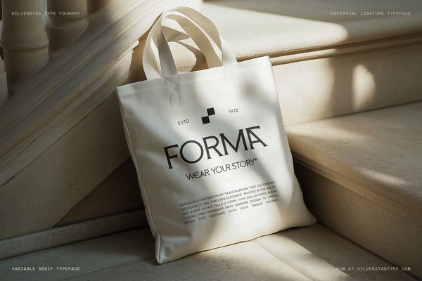 SLTF Arcilla Semi Bold used in FORMA fashion brand identity — a cream canvas tote bag printed with the FORMA wordmark, ESTD 1972 logo mark, and the tagline WEAR YOUR STORY*, photographed on marble steps in warm sunlight with architectural shadows. Demonstrates Arcilla in contemporary streetwear and fashion retail branding.